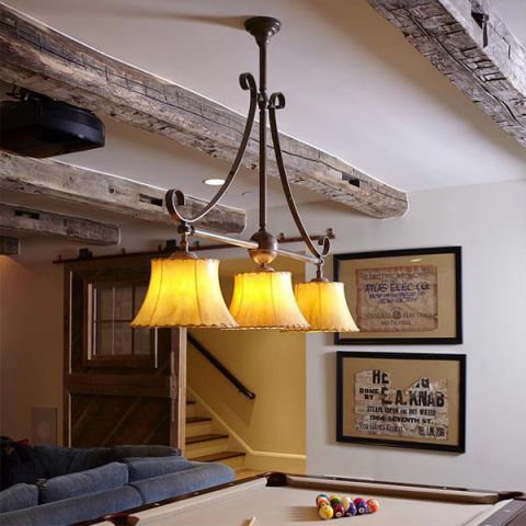 Shoreland Scroll Chandelier with sheepskin shades lights a billiards table.