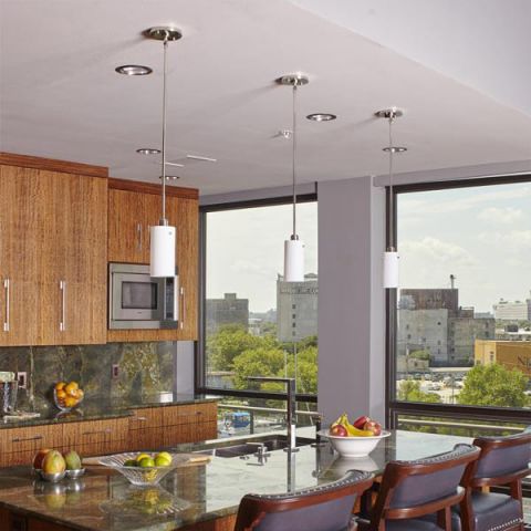 A trio of One Light Tribeca Pendants over top of an island in a modern condo kitchen.
